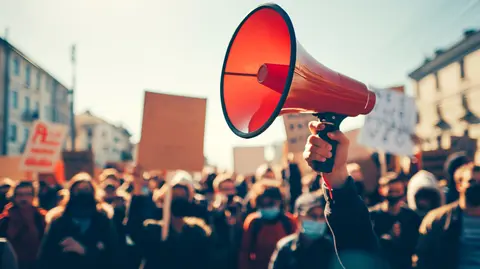 An activist protesting with megaphone during a strike with group of demonstrator all around